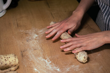 Fototapeta premium Female hands making a homemade baguette from whole grain flour. Healthy food