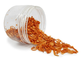 Crispy fried red onions spilling out from an open plastic clear jar isolated on white background. Sliced shallots are deep-fried into golden brown color. Also known as Bawang Goreng in Indonesia.