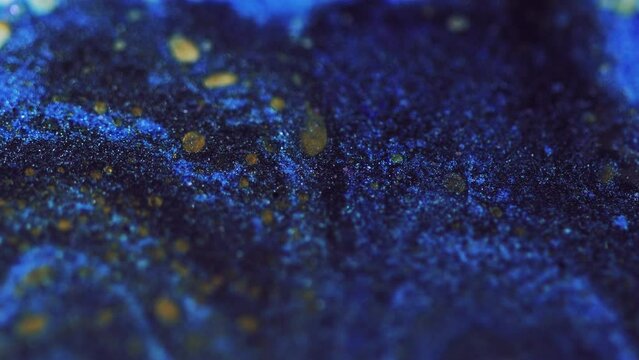 Wet glitter texture. Paint flow. Defocused blue gold color shimmering particles acrylic ink water wave motion on dark abstract art background.