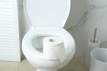 New paper roll on toilet bowl in bathroom