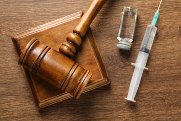 Law concept. Gavel, syringe and glass vial on wooden table, top view