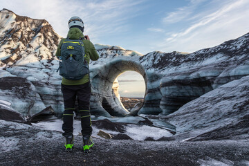 A guy standing in front of the arch of Katla Glacier in Iceland