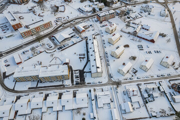 Aerial view of residential area in Sweden with low-rise and private buildings during winter. Snowy weather, snowfall in a little European village, town, city.