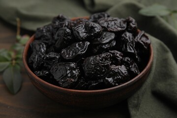 Sweet dried prunes in bowl on table, closeup