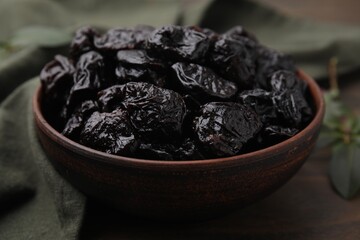Sweet dried prunes in bowl on table, closeup