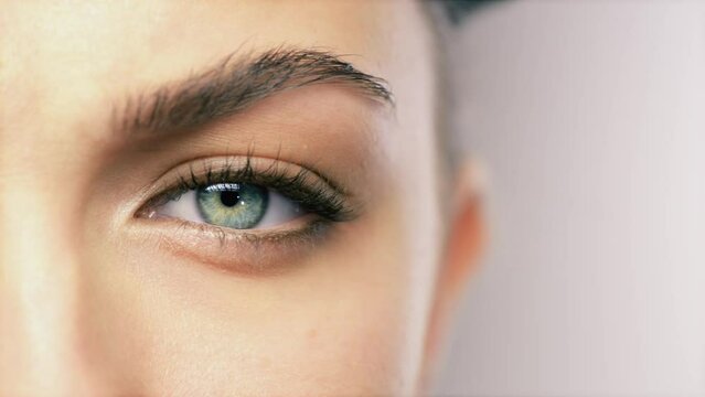 Portrait, closeup and eye of person, vision and human blink isolated on a white studio background mockup space. Face macro, eyebrow and eyeball of model, healthy eyelashes and beauty of green iris