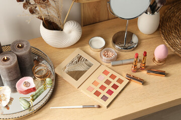 Burning candles, jewelry and makeup products on wooden dressing table
