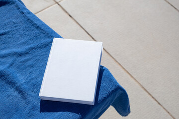 blank book for mockup design on lounger by the swimming pool