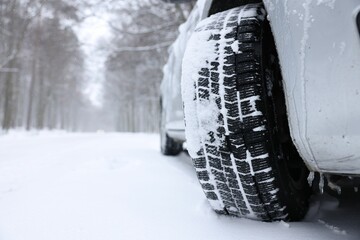 Car with winter tires on snowy road outdoors, closeup. Space for text