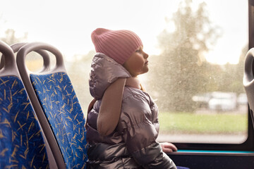 Side view of child girl 5 year old riders on public bus metropolitan transport, looking ahead. Cute...