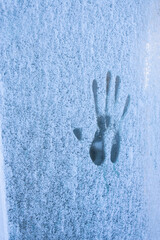 A palm print on a frozen window. Natural winter background