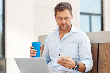 Young man checking email using a laptop while sitting on the street