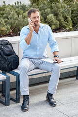 Business concept, business man calling on the phone while sitting outdoors with a laptop