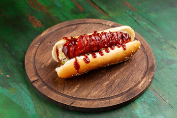 Hot dog, bun with sausage and ketchup on a wooden board. Fast food.