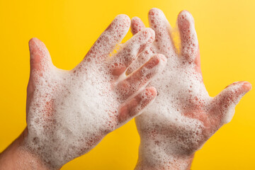 Soap foam in a man's hand on a yellow background.