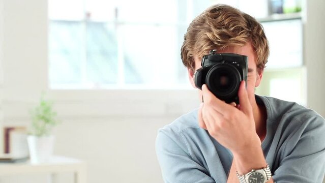 Camera, photography and face of man in home for creative career, job and working. Happy, photographer and portrait of person in apartment with digital equipment for taking pictures for portfolio