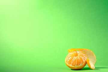 A peeled clementines against a seamless green background