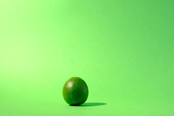 Single lime citrus fruit against a seamless green background
