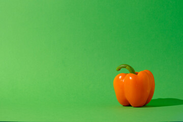 Orange bell pepper against a seamless green background