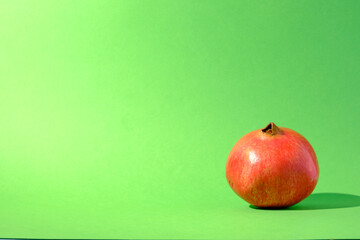 Single pomegranate against a seamless green background