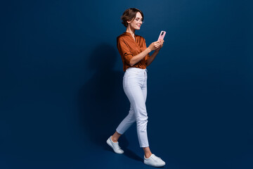 Fototapeta na wymiar Full length photo of sweet pretty lady wear brown shirt texting apple iphone samsung modern gadget isolated blue color background