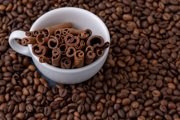 Coffee beans and cinnamon sticks in a cup. Food drink background