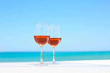 Two glasses of rose wine against blue water and sea