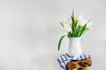 Tulips bouquet in white vase on wooden rustic chair