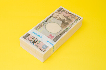 100万円の札束が3つ積みあがった様子　300万円　黄色背景