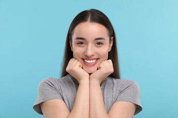 Young woman with clean teeth smiling on light blue background