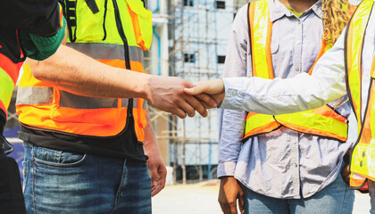 Handshake cooperation of architects and male and female workers multiethnicon on the apartment construction site condominium building for success in the project teamwork and achieving goals.