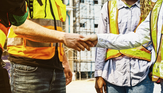 Handshake cooperation of architects and male and female workers multiethnicon on the apartment construction site condominium building for success in the project teamwork and achieving goals.