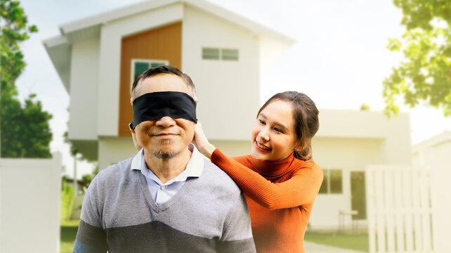 Beautiful eldest daughter covers her eyes with black cloth secret surprise retired father makes invisible standing together in front of newly renovated house happiness with beautiful new home.