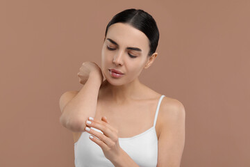 Woman with dry skin checking her elbow on beige background