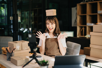 Fashion blogger concept, Young Asian women selling clothes on video streaming.Startup small business SME, using smartphone or tablet taking receive and checking.