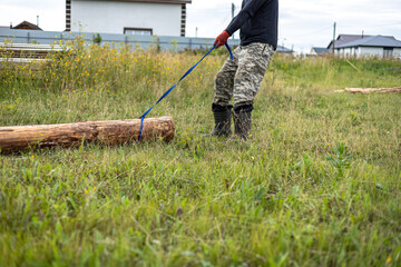 A man pulls a wooden log on new development area for summerhouses.  Hard manual work concept...