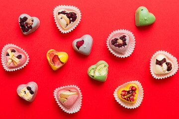chocolate sweets in the form of a heart with fruits and nuts on a colored background. top view with space for text, holiday concept
