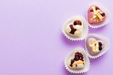 chocolate sweets in the form of a heart with fruits and nuts on a colored background. top view with space for text, holiday concept