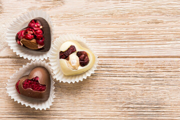 chocolate sweets in the form of a heart with fruits and nuts on a colored background. top view with space for text, holiday concept