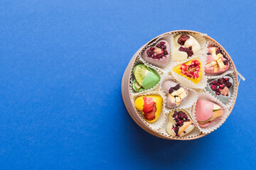 Holiday composition: sweet candy, with gift boxes with bow and chocolate hearts, photo template, background. Top View with copy space on colored background