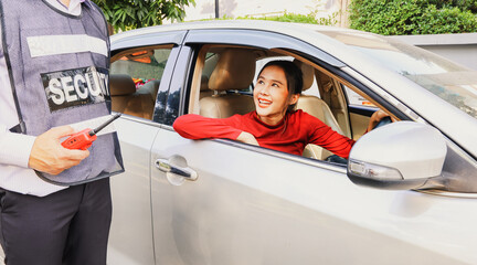 Asian woman driving car asks travel assistance and asks the senior male security guard standing provide friendly and polite service receives assistance in solving immediate problems efficiently.