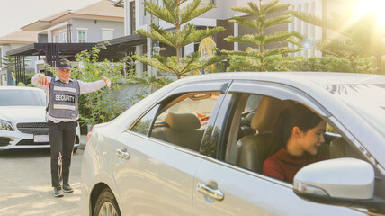 Fototapeta premium Senior security guards take care female residents with friendliness facilitating parking on the sidewalk providing friendly service with smile to the female residents driving carefully for safety.