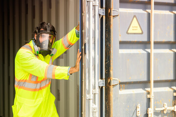Male rescue worker wearing uniform PPE and wear mask to prevent accidents from dangerous stench toxins inside the container that are illegally transported into the country. Open the door carefully.