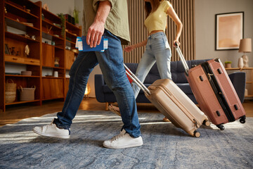 Closeup man and woman walking with luggage leaving home - obrazy, fototapety, plakaty