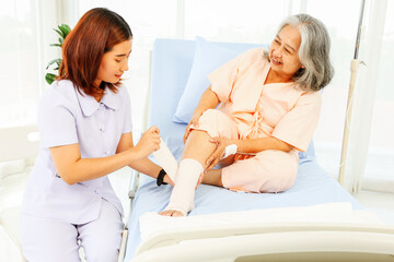 Female nurse care elderly female patient hospitalized patient with ankle pain from sprained foot...