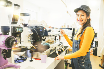 Beautiful asian female barista dressed bright yellow lifestyle outfit runs coffee shop selling food...