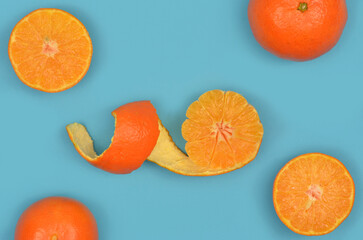 Tangerines, slices of mandarines and tangerine peel on a blue background. 