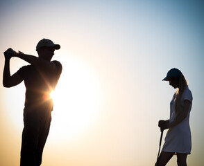Male and female golfers at sunset