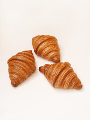 Fresh 3 French croissants with shadows on white background and space for text.