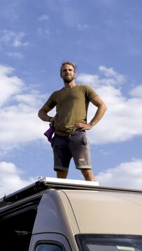 Man Proudly Standing on Top of a Camper Van